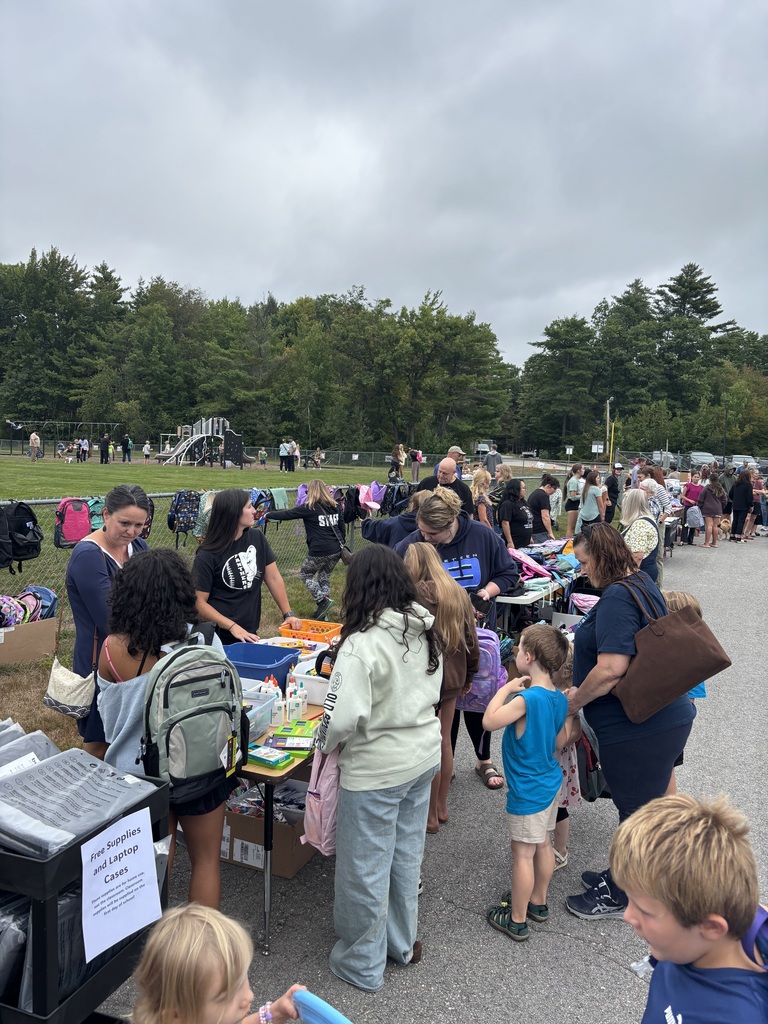 A picture of families at the Wakefield BBQ, standing outside talking and getting backpacks