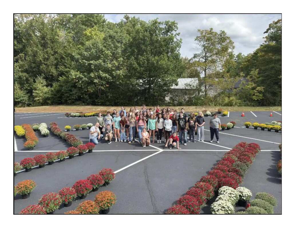 students standing in the middle of a parking lot surrounded by different colored mums