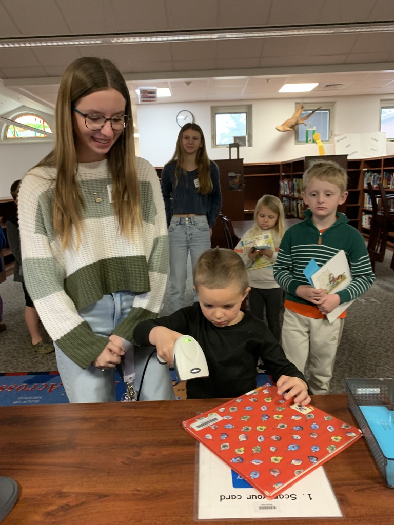 High school students helping Riversick elementary kindergarten students check out their first books.