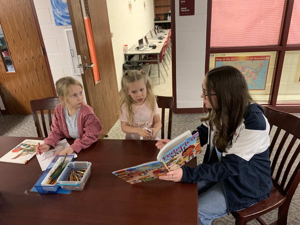 High school students helping Riversick elementary kindergarten students check out their first books.