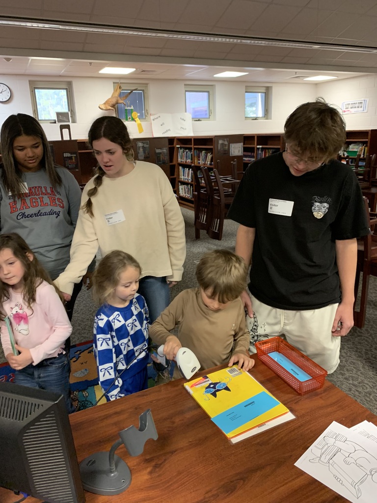 High school students helping Riversick elementary kindergarten students check out their first books.