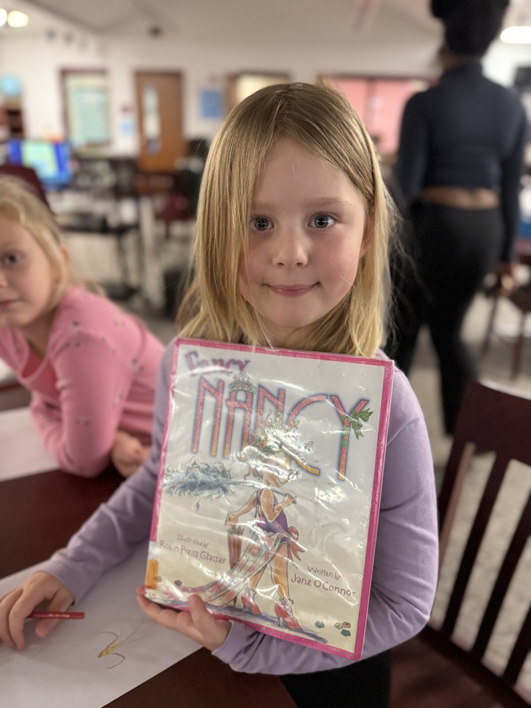 High school students helping Riversick elementary kindergarten students check out their first books.