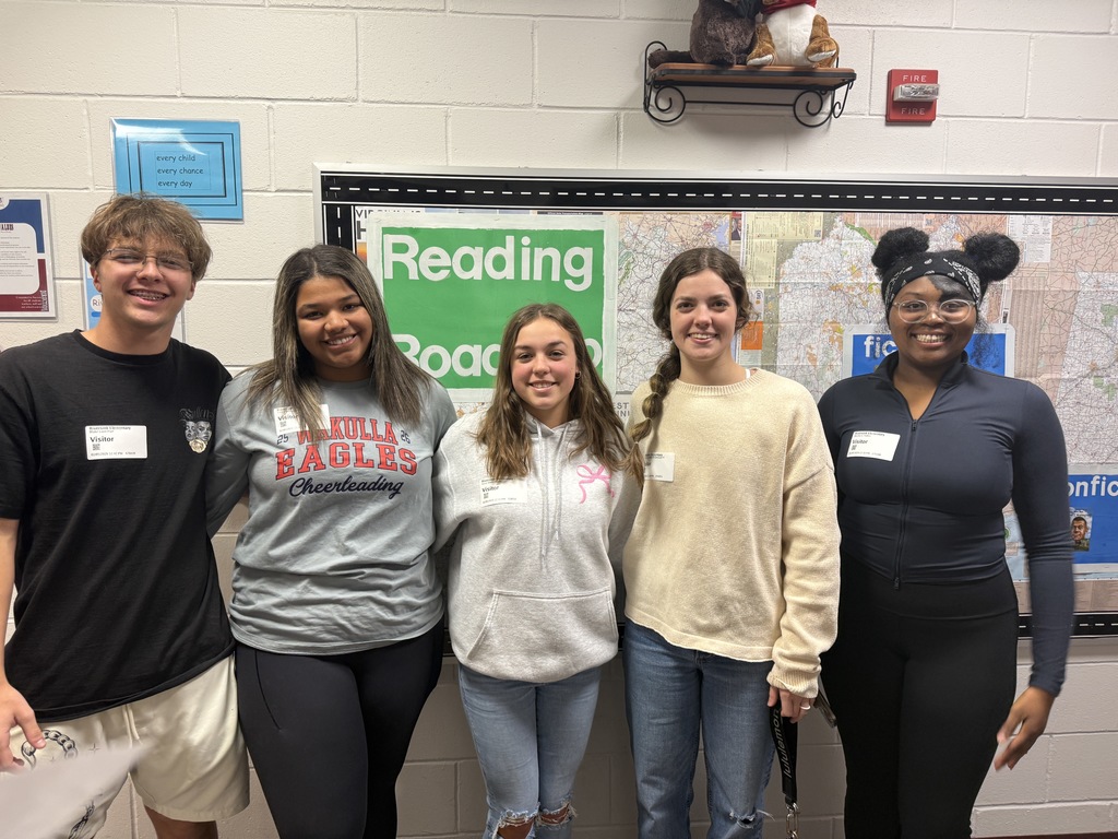 High school students helping Riversick elementary kindergarten students check out their first books.
