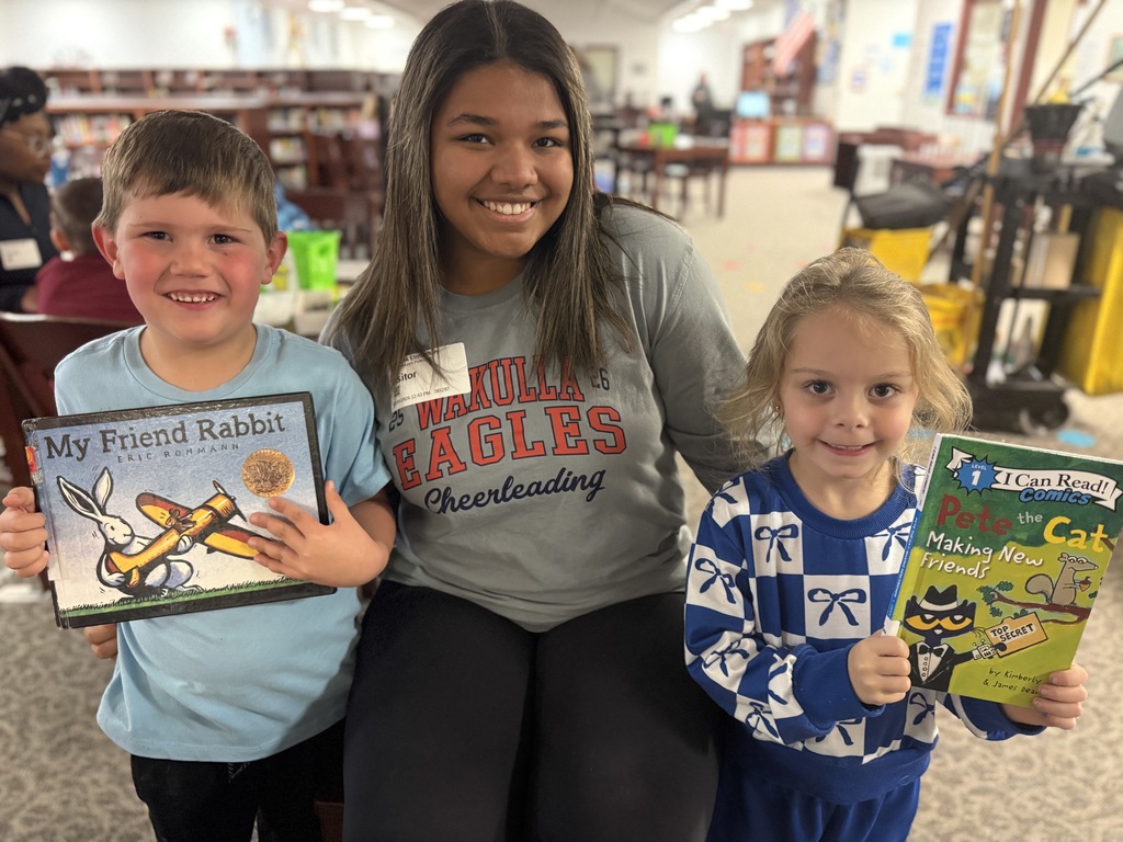 High school students helping Riversick elementary kindergarten students check out their first books.