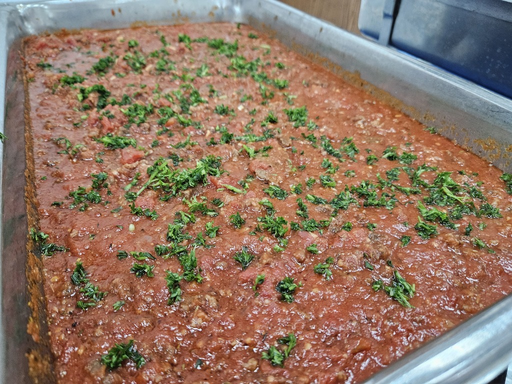 Large tray of spaghetti meat sauce topped with fresh herbs.