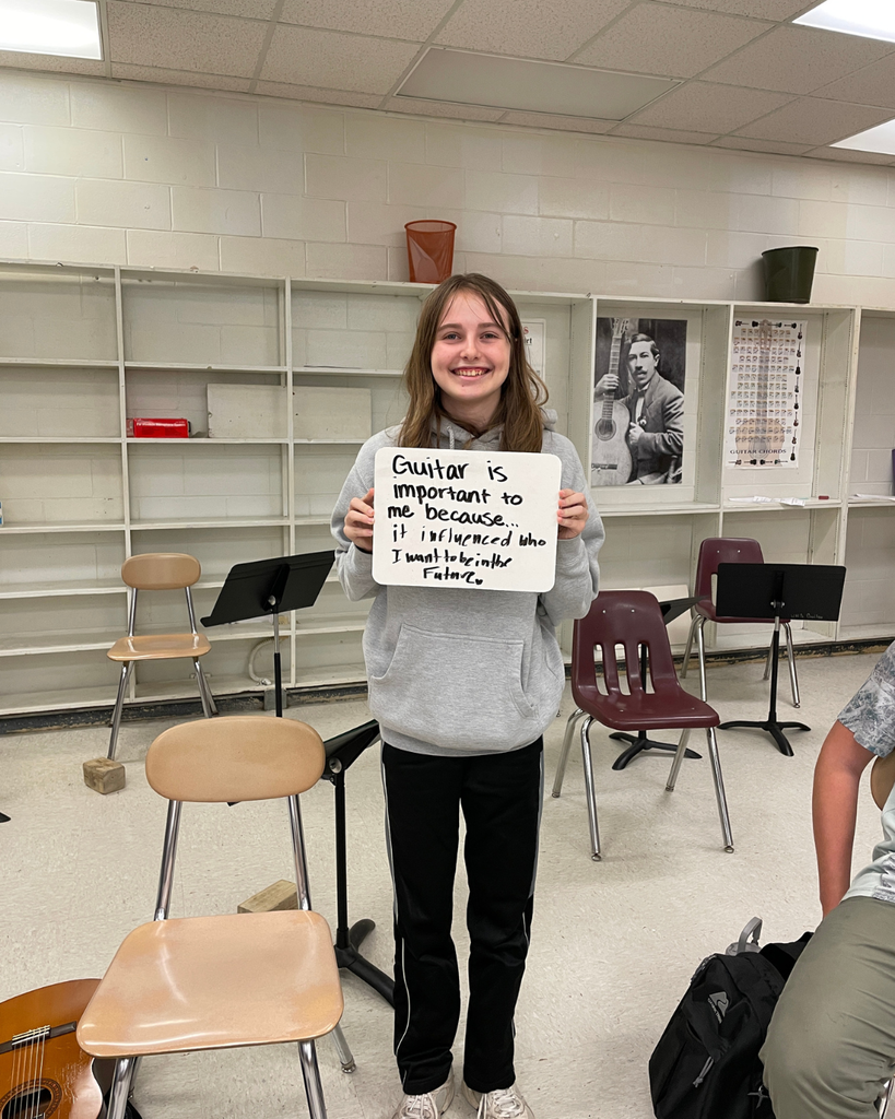 The image pictures a student with a sign that says,"guitar is important to me because... it influenced who I want to be in the future"