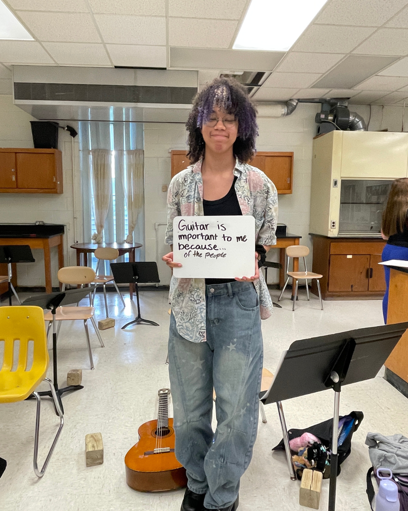 The image pictures a student with a sign that says,"Guitar is important to me because... of the people"