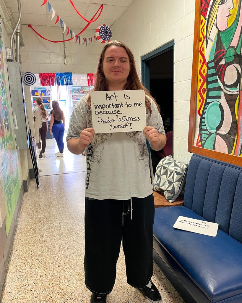 The image pictures a student with a sign that says,"Art is important to me because... freedom to express yourself!"