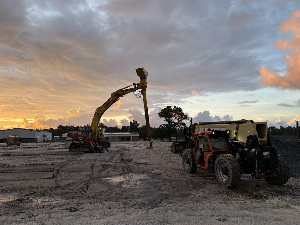 Crews are installing rammed aggregate piers—columns of compacted stone that strengthen the soil before the concrete foundation is poured.