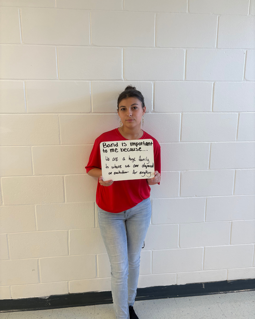A student holding a sign saying,"Band is important to me because...we are a huge family to where we can depend on each other for anything."