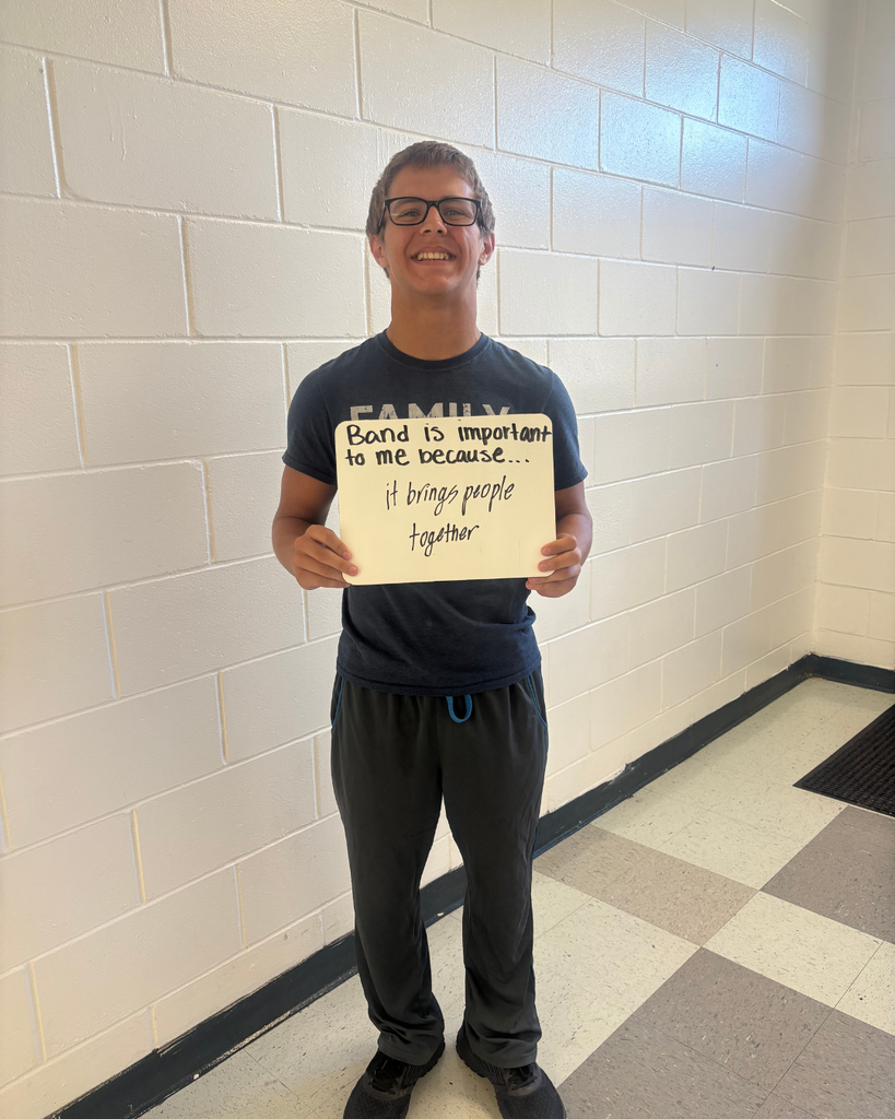 A student holding a sign saying,"Band is important to me because...it brings people together"