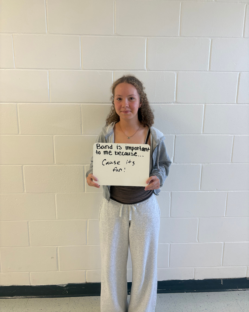 A student holding a sign saying,"Band is important to me because...cause it's fun!"
