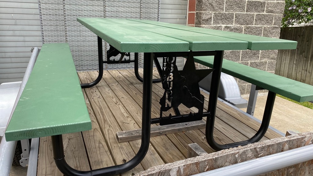 Green picnic table with black legs.
