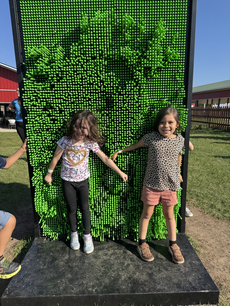 2 students in front of a green wall