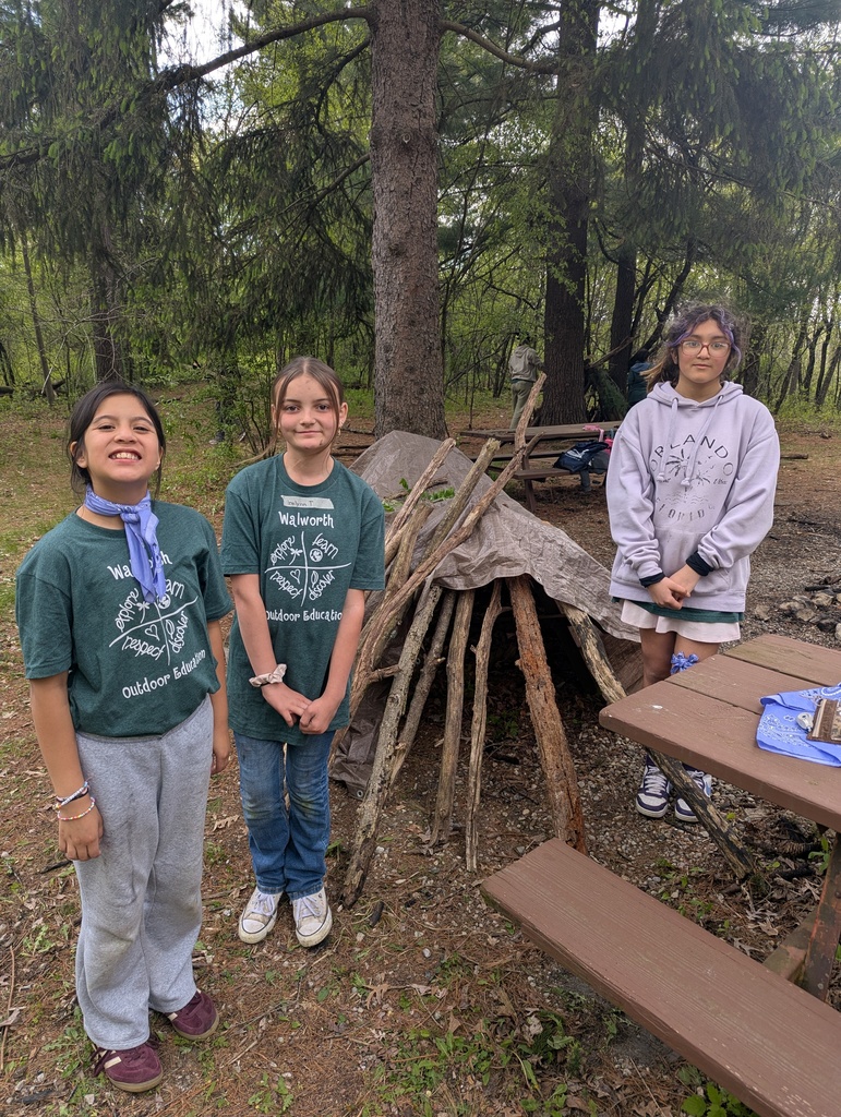 three kids in front of a stick fort
