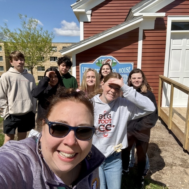 8th graders in front of a small red building