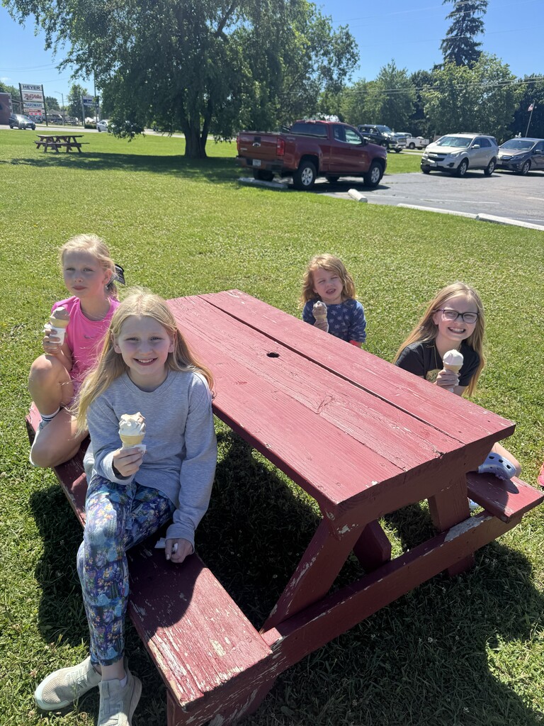 Students at a picnic table eating ice cream. 