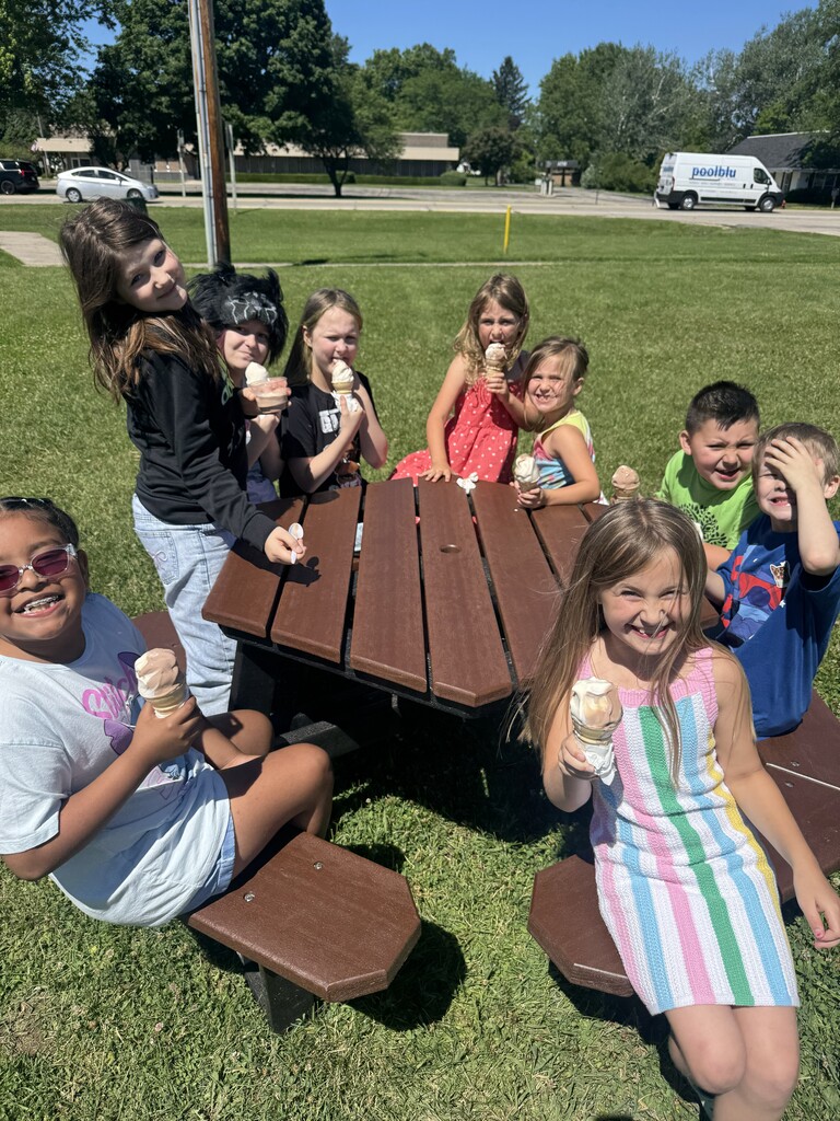 Students at a picnic table eating ice cream. 