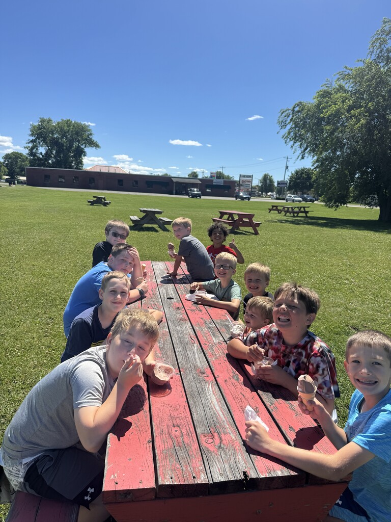Students at a picnic table eating ice cream. 