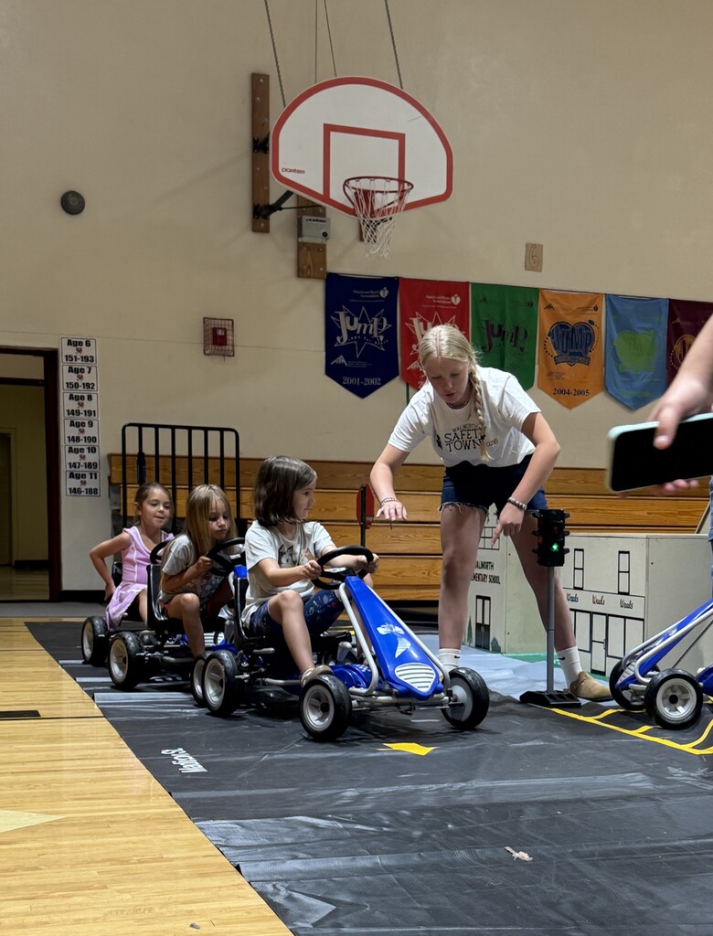 Student riding pedal cars and learning safety rules.
