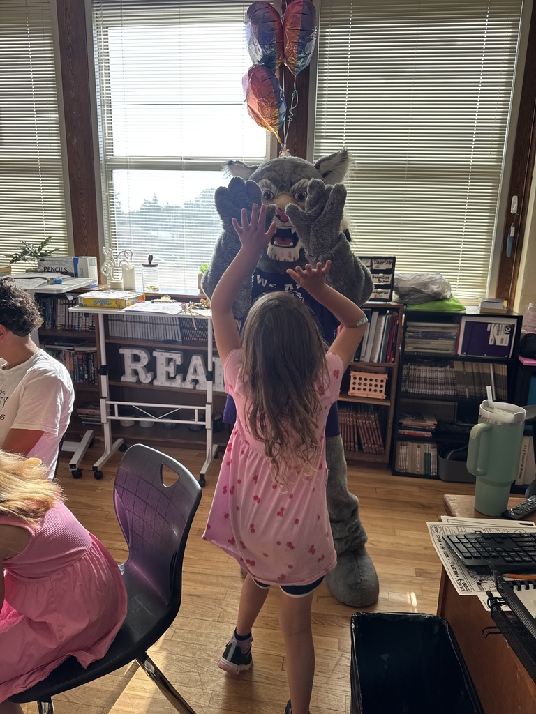 Student high fiving Wesley the Wildcat. 