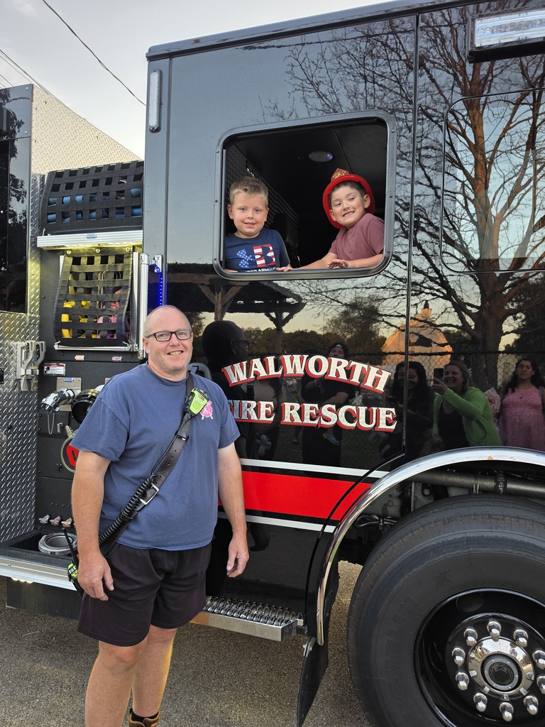 Two children and an adult by Walworth Fire and Rescue black fire truck