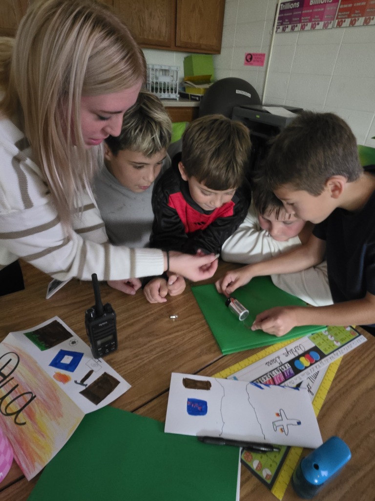 Students and teacher lighting a lightbulb with a battery.