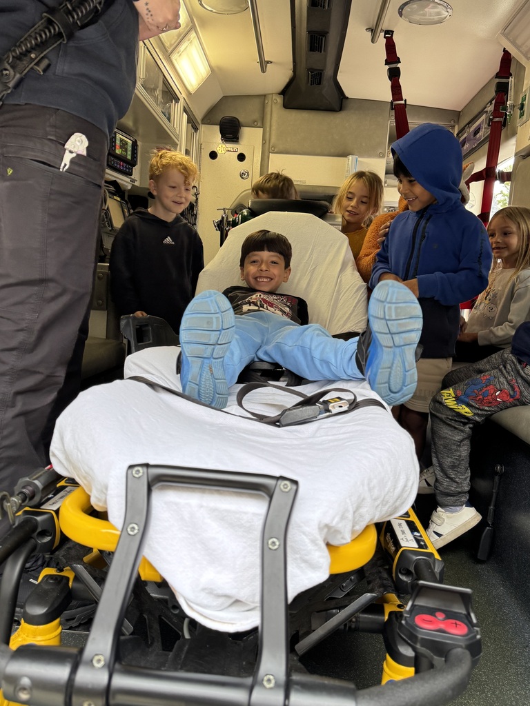 Students learning about the parts of the ambulance and one student is on a stretcher. 