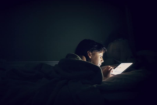 student in bed with a bright screen