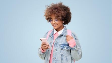 Girl with backpack and jean jacket navigating cell phone