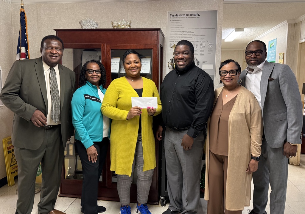 A donation received from Cooks Chapel Missionary Baptist Church. 6 people standing. One in the middle holding a check