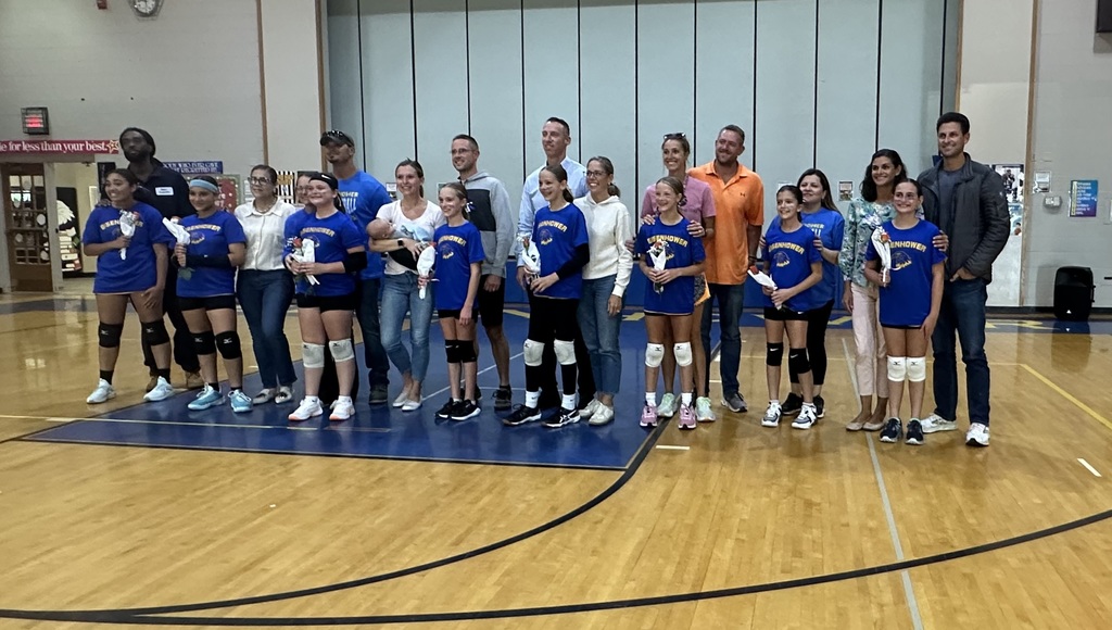 Students playing volleyball inside a gym.