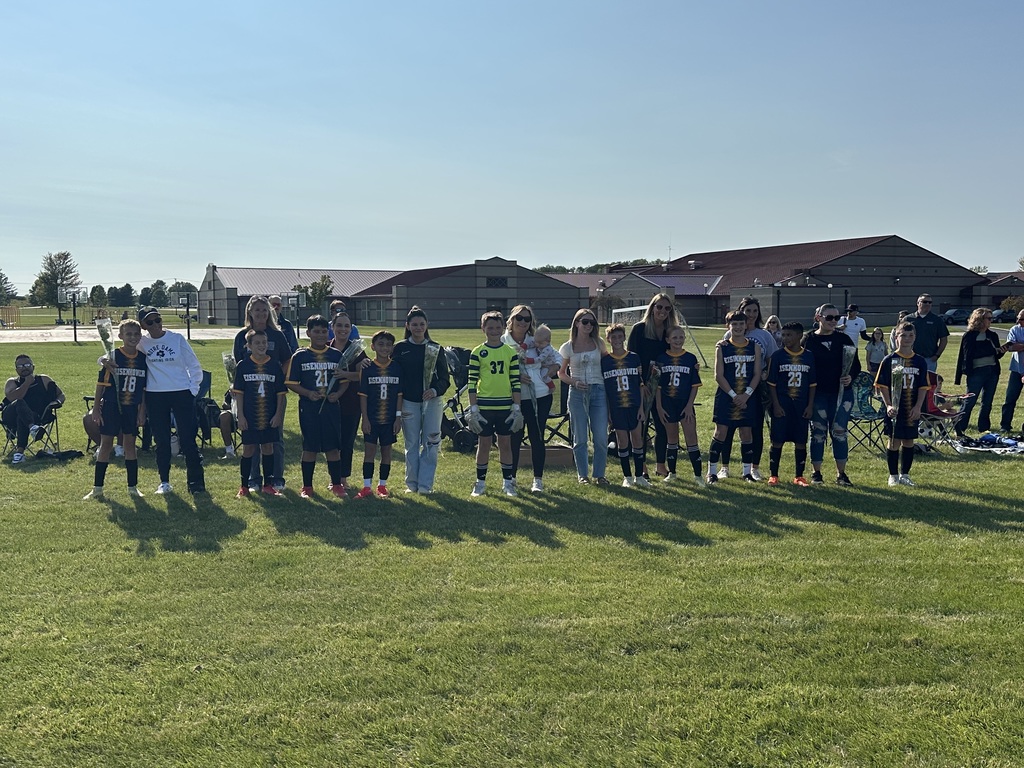 Students playing soccer outside on a green soccer field.