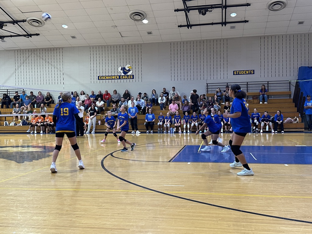 Students playing volleyball inside a gym.