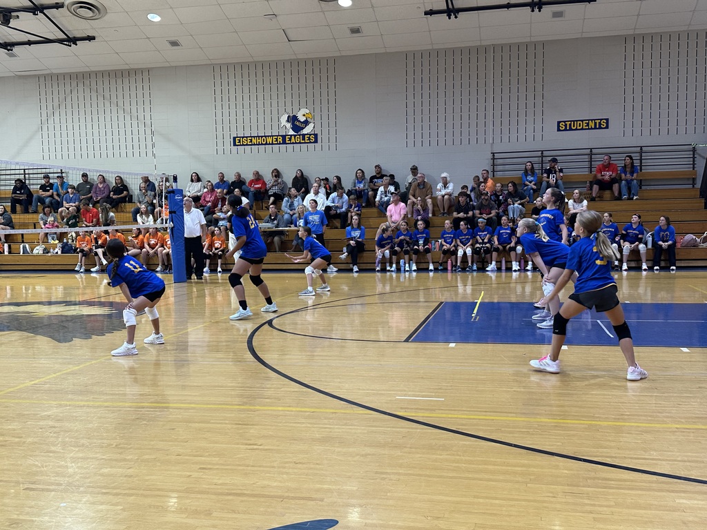 Students playing volleyball inside a gym.