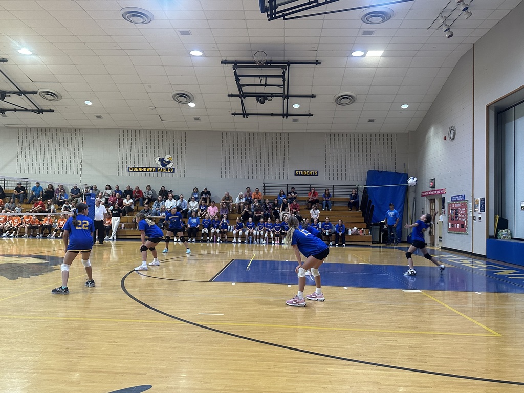 Students playing volleyball inside a gym.