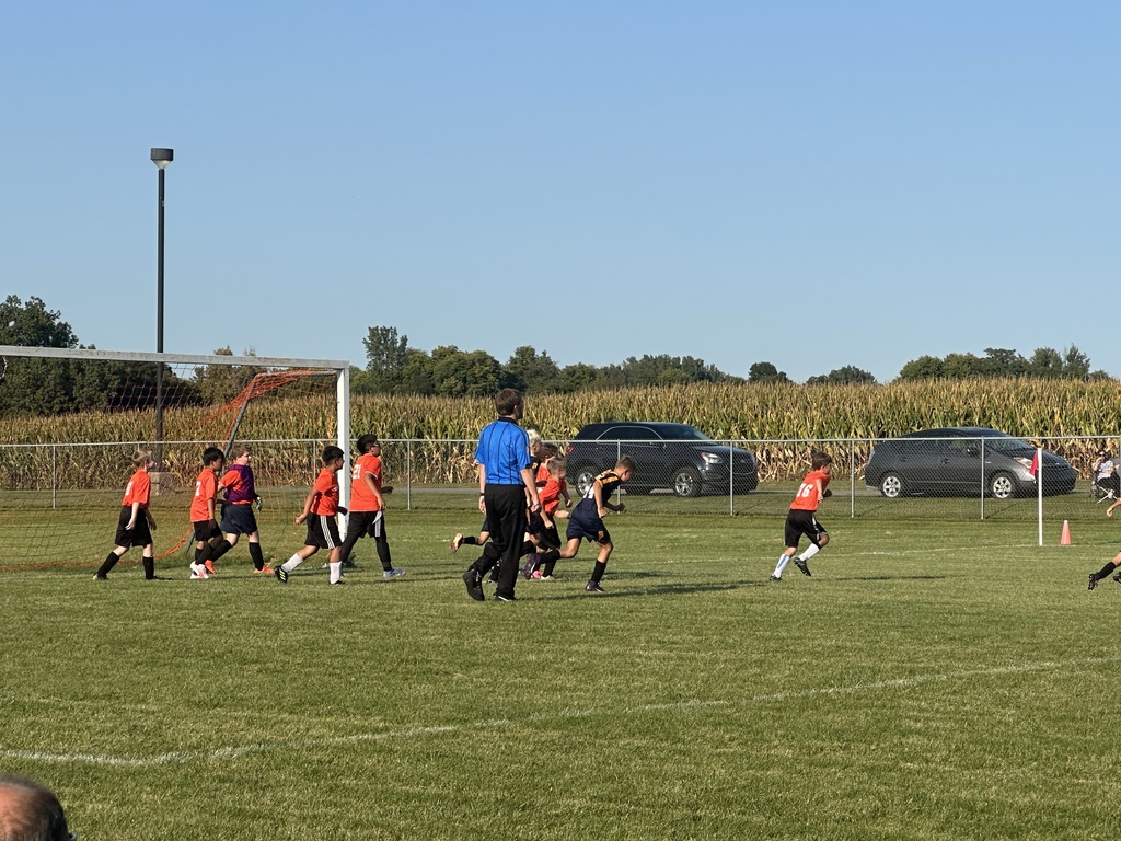 Students playing soccer outside on a green soccer field.