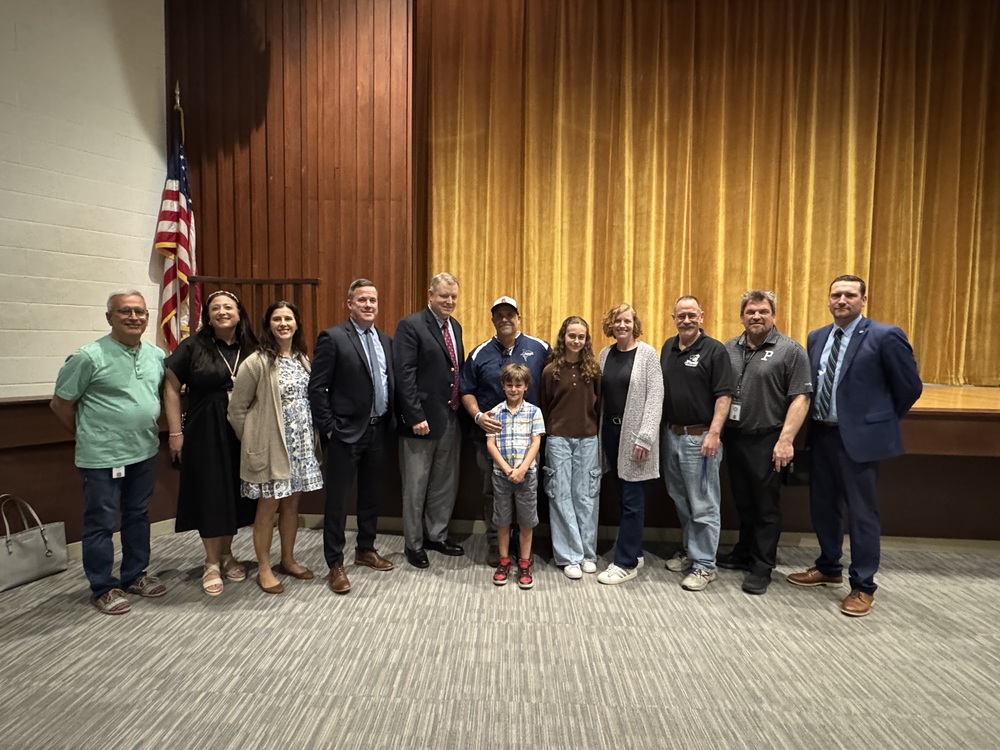 Dr. Michael Xiahros (center with baseball hat) is surrounded by family and co-workers along with Superintendent William McCaffrey, Executive Director of Secondary Education Tim Kane, School Committee Chairperson Shaun Galligan and Pilgrim Principal Toby Gibbons. Xiarhos is the Warwick Schools Teacher of the Year