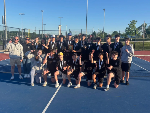 Group of boys wearing black posing with coaches and medals on a tennis court 