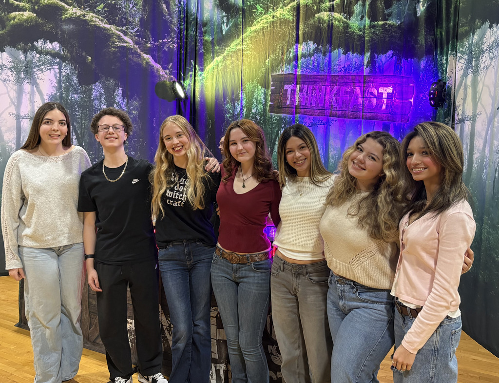 7 students in front of the Thinkfast sign in the gym