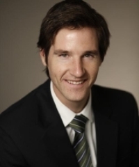 Dr. David Knight headshot. Man with short brown hair, wearing a black tie and striped tie.
