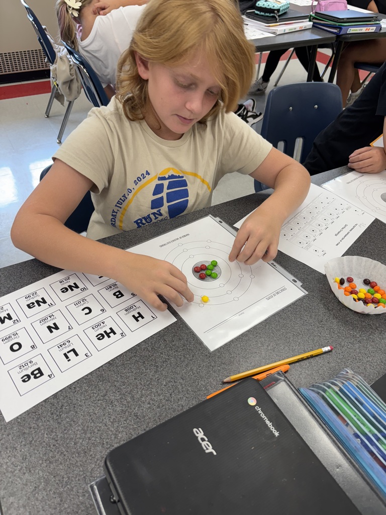 A student uses candy to model the structure of atoms.