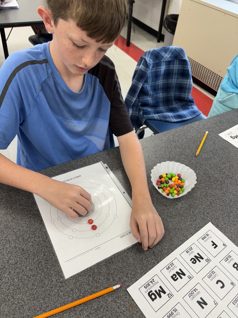 A student uses candy to model the structure of atoms.