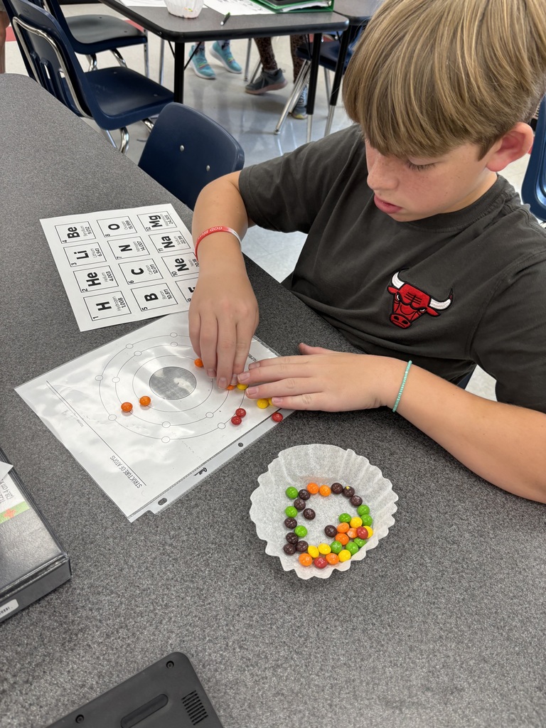 A student uses candy to model the structure of atoms.