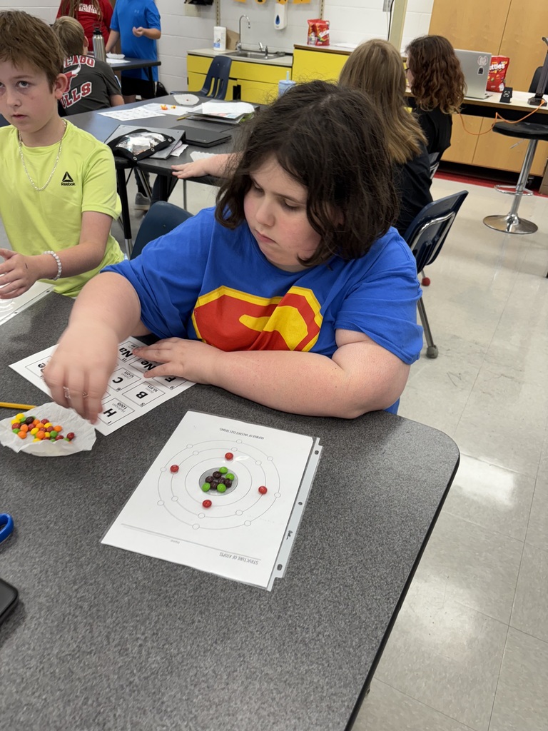 A student uses candy to model the structure of atoms.