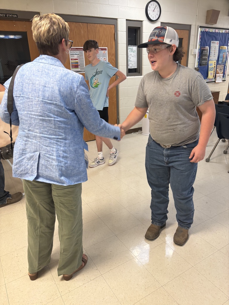 A student shakes his principal's hand.