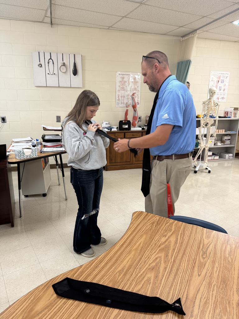 A man shows a student how to tie a tie.