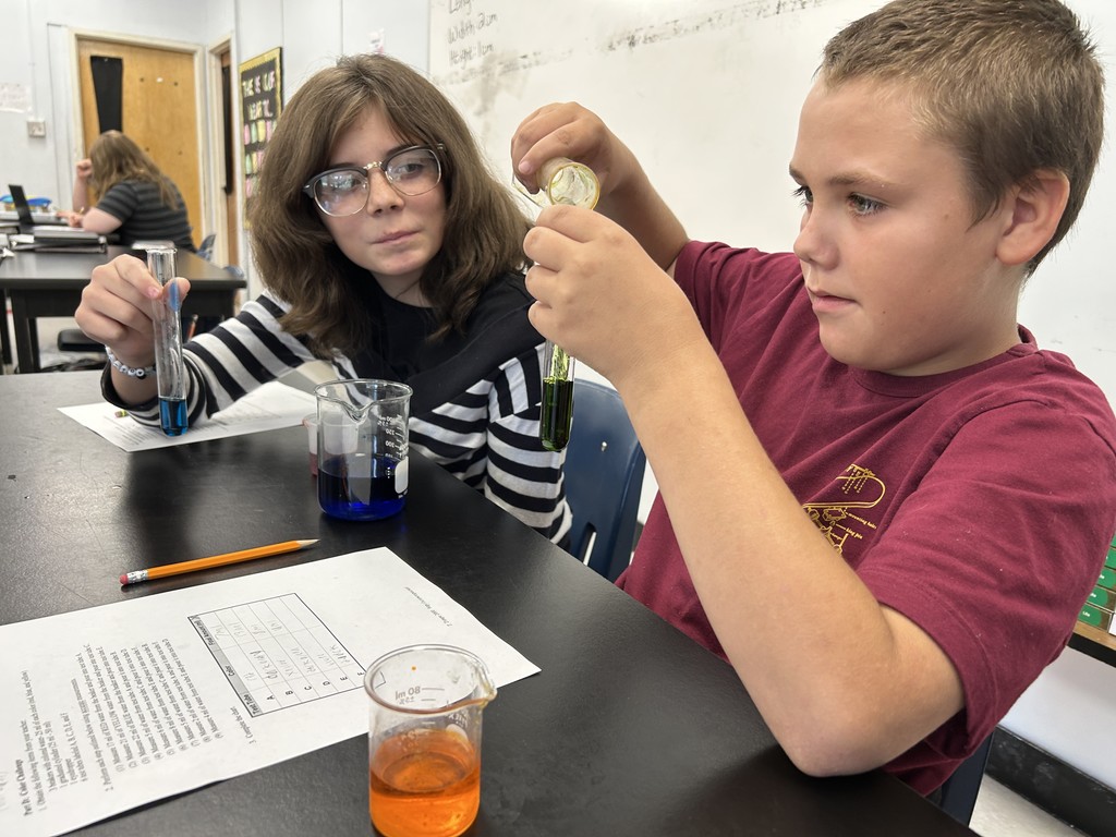A student pours liquid from a beaker into a graduated cylinder. 