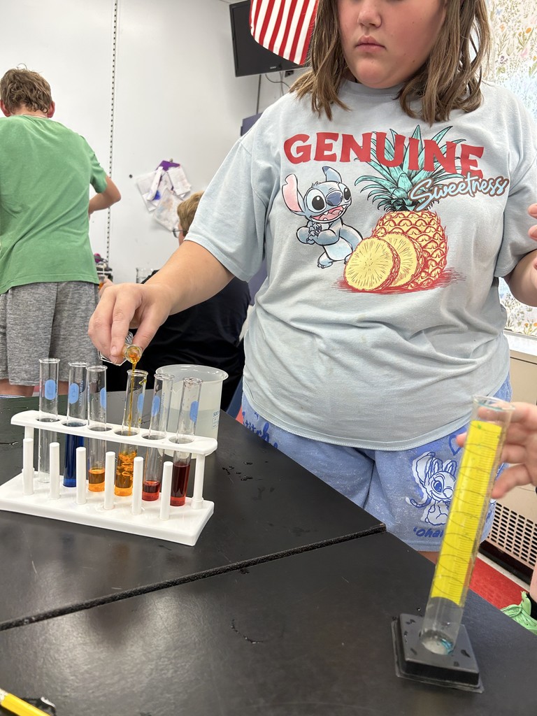 A student pours liquid from a beaker into a graduated cylinder. 