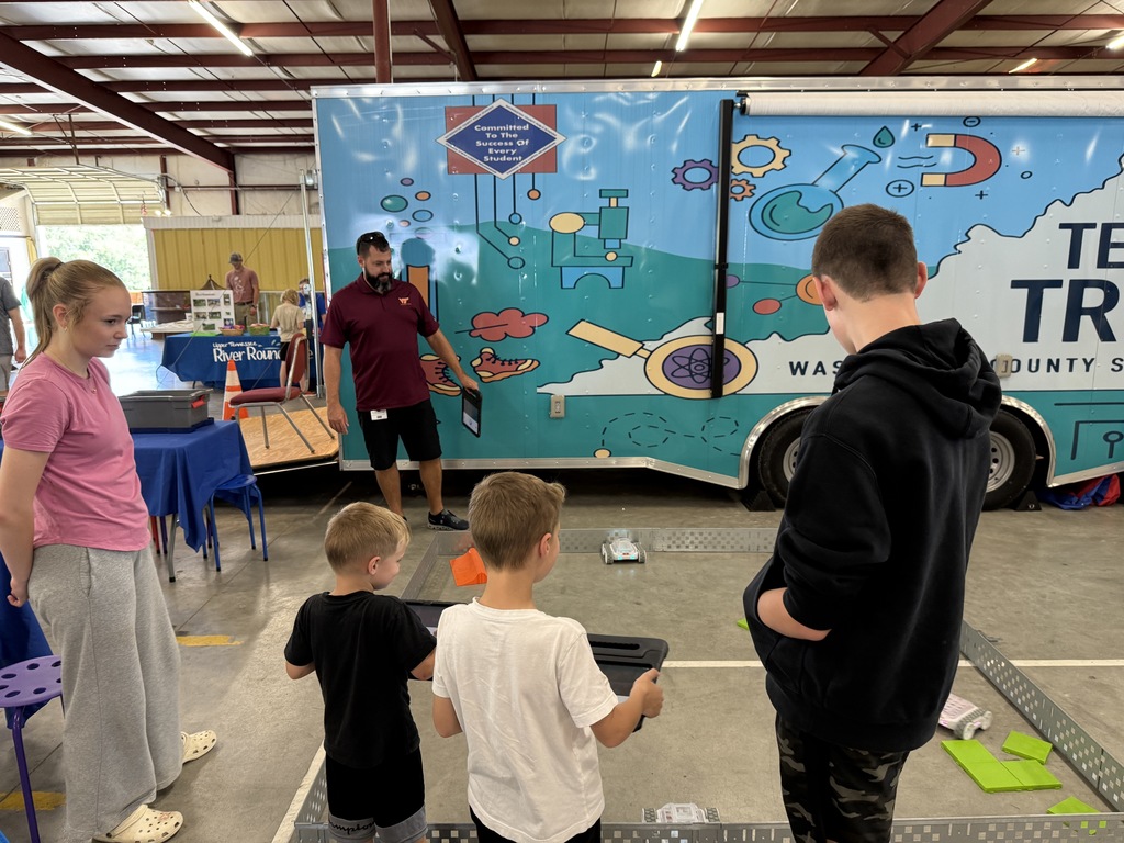 Older students help younger students drive robots.